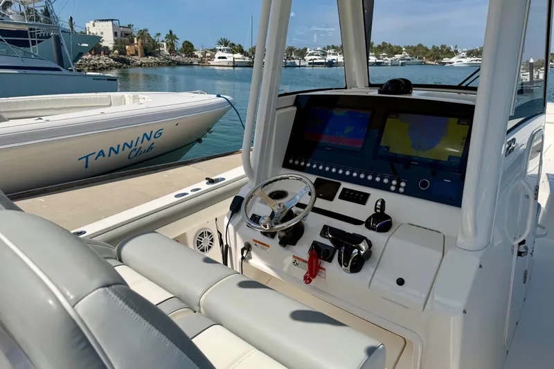 Slide: The Image of 2022 Regulator 28 boat dashboard with advanced navigation system, docked near Tanning Club boat. - 6