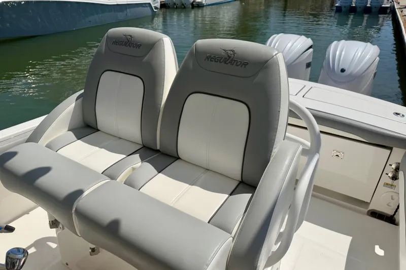 Slide: The Image of 2022 Regulator 28 boat with dual cushioned seats and twin engines at dock. - 7