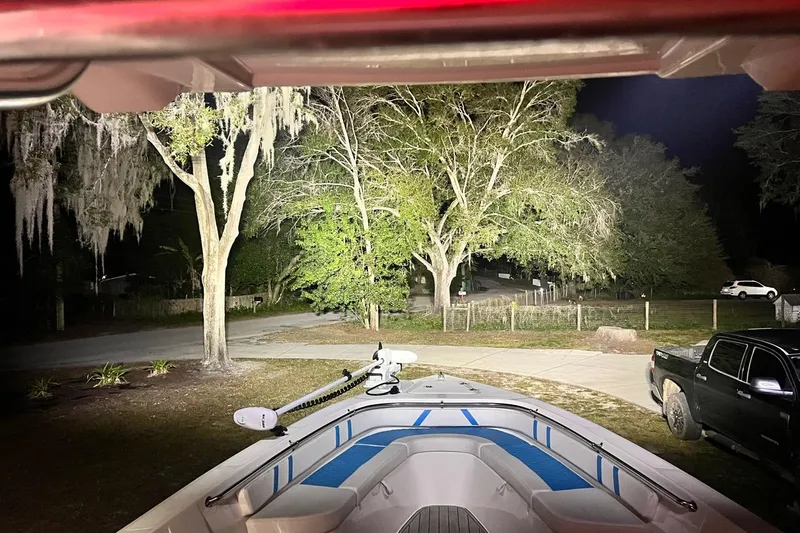 Slide: The Image of Custom Infusion 34 CC boat parked at night, illuminated by bright lights, with trees in the background. - 91