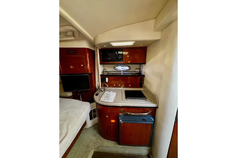Slide: The Image of 2007 Sea Ray 290 Sundancer interior with kitchenette, microwave, and TV. Luxurious wood finish. - 18