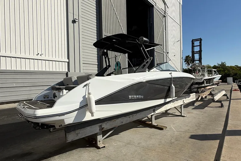 Slide: The Image of 2021 Scarab 255 ID boat on trailer outside a large warehouse. - 2