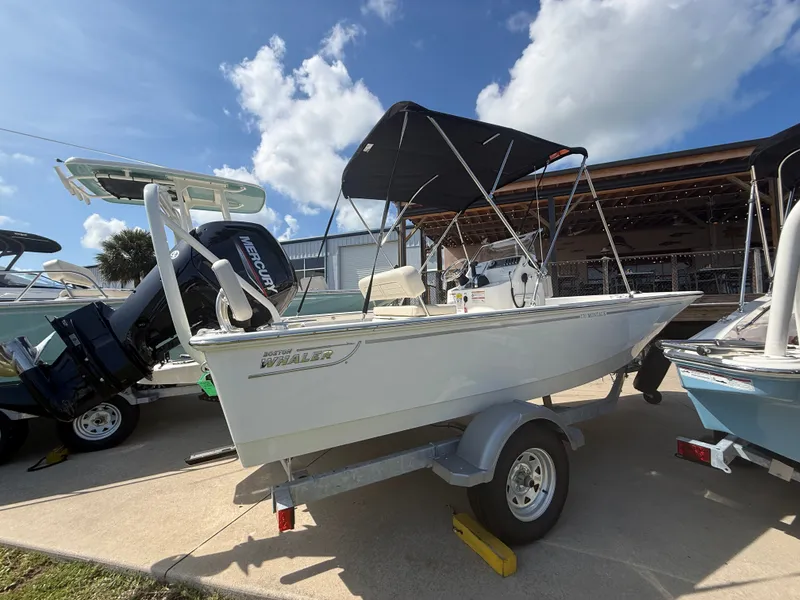 Slide: The Image of A 2027 Boston Whaler 170 Montauk on a trailer. It features a black Bimini top. - 2