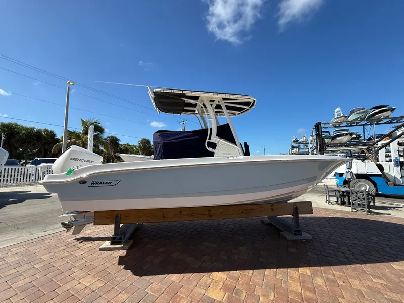 Slide: The Image of A 2027 Boston Whaler 220 Dauntless is on a paved area under a blue sky. - 6