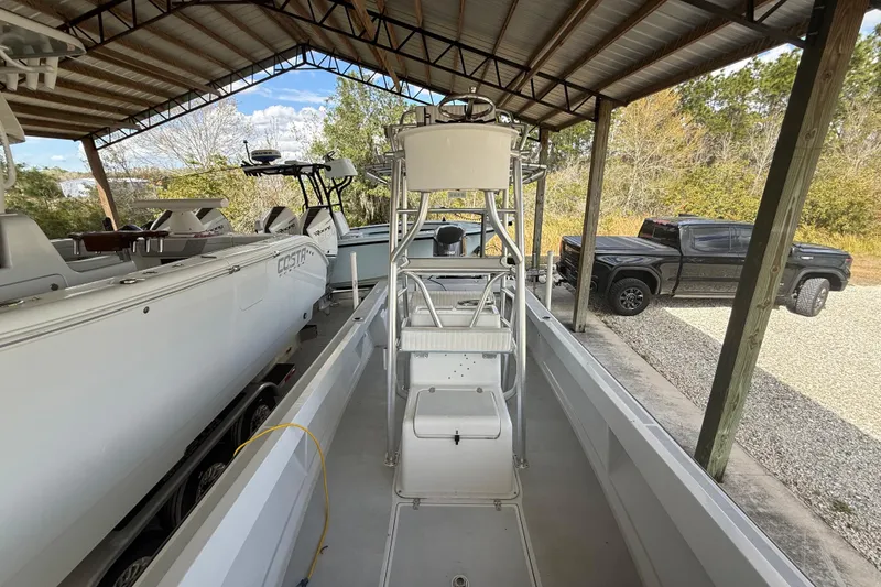 Slide: The Image of 1974 Aquasport 2400 Center Console boat under a metal canopy, with nearby vehicles. - 31