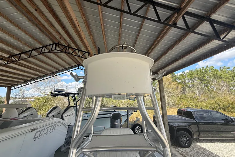 Slide: The Image of 1974 Aquasport 2400 Center Console boat under a metal canopy, surrounded by trees and vehicles. - 32