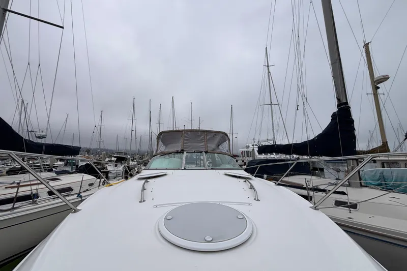 Slide: The Image of 2004 Larson 310 boat docked in a marina, surrounded by sailboats under cloudy skies. - 10