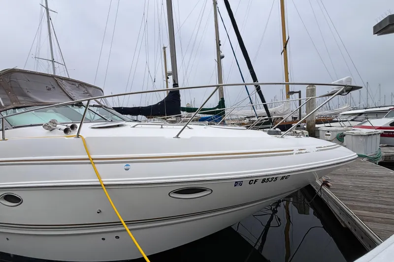 Slide: The Image of 2004 Larson 310 boat docked at marina, surrounded by other sailboats. - 11