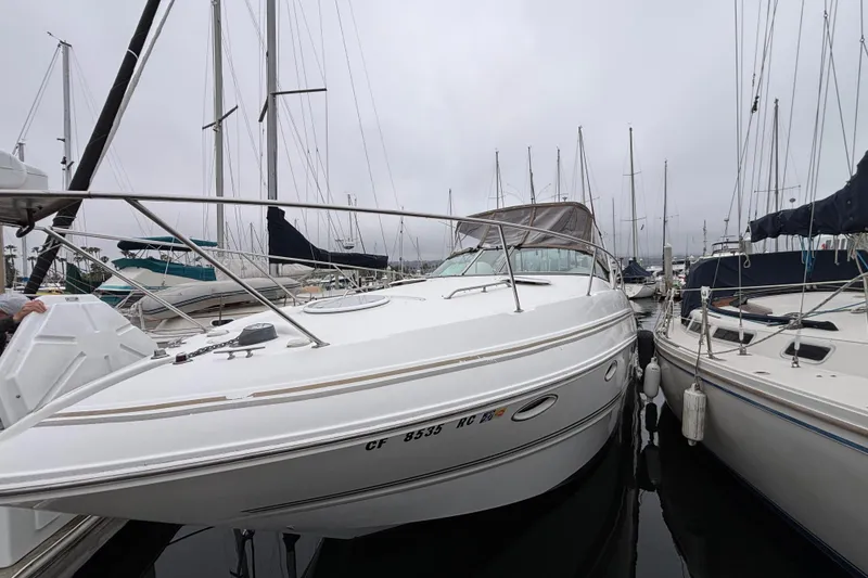 Slide: The Image of 2004 Larson 310 boat docked among sailboats in a marina on a cloudy day. - 12
