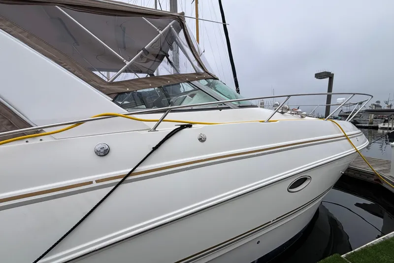 Slide: The Image of 2004 Larson 310 boat docked at marina, featuring sleek white exterior and chrome railings. - 13