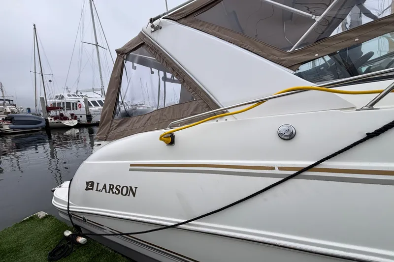 Slide: The Image of 2004 Larson 310 boat docked at marina with other vessels in background. - 16