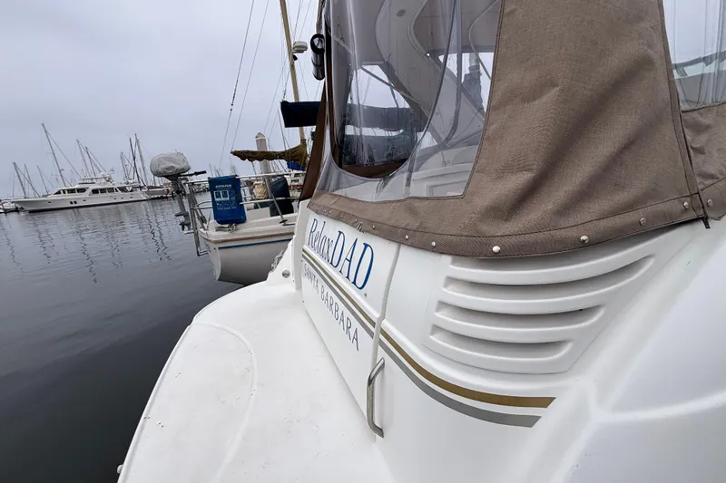 Slide: The Image of 2004 Larson 310 boat docked in a marina, featuring a beige canopy and calm waters. - 17