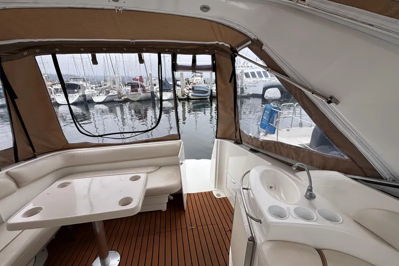 Slide: The Image of Interior of a 2004 Larson 310 boat with seating, table, and marina view. - 23