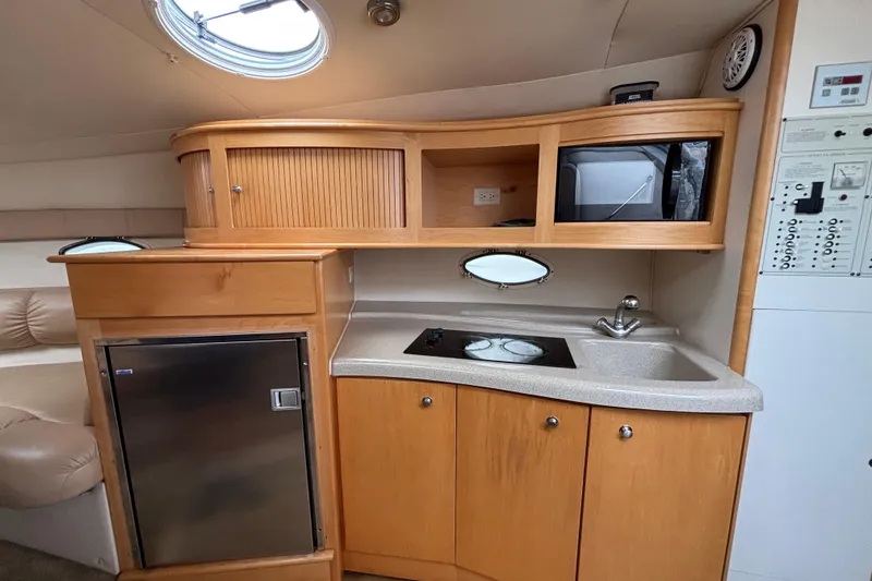 Slide: The Image of 2004 Larson 310 boat interior kitchen with wooden cabinets, sink, stove, and refrigerator. - 39