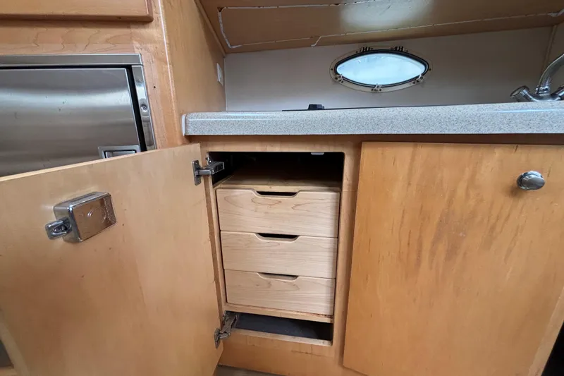 Slide: The Image of 2004 Larson 310 boat interior with open wooden cabinet and drawers. - 41