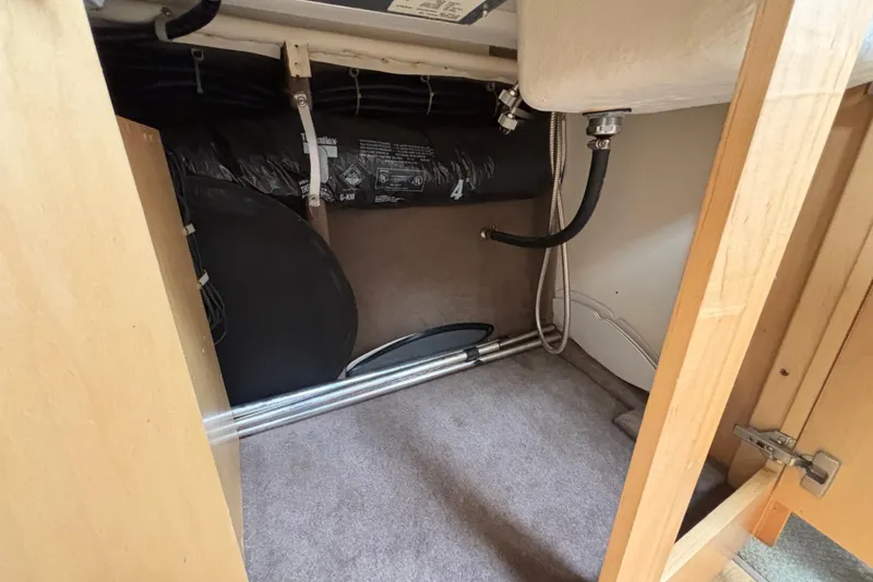 Slide: The Image of Interior storage compartment of a 2004 Larson 310 boat, showing pipes and insulation. - 42