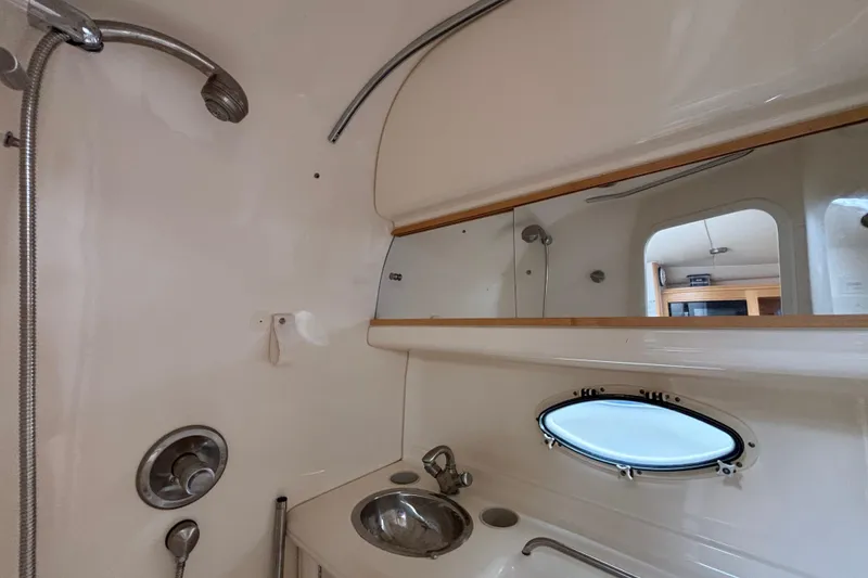 Slide: The Image of Bathroom interior of a 2004 Larson 310 boat with sink, mirror, and porthole window. - 45