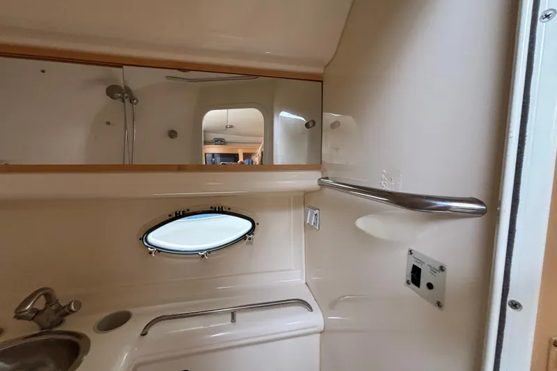 Slide: The Image of 2004 Larson 310 boat bathroom interior with sink, mirror, and porthole window. - 46