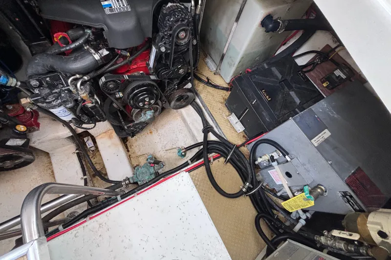 Slide: The Image of Engine compartment of a 2004 Larson 310 boat, showcasing mechanical components and wiring. - 52