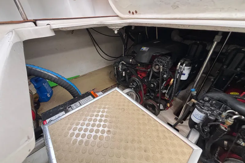 Slide: The Image of Engine compartment of a 2004 Larson 310 boat, showcasing mechanical components and hoses. - 54