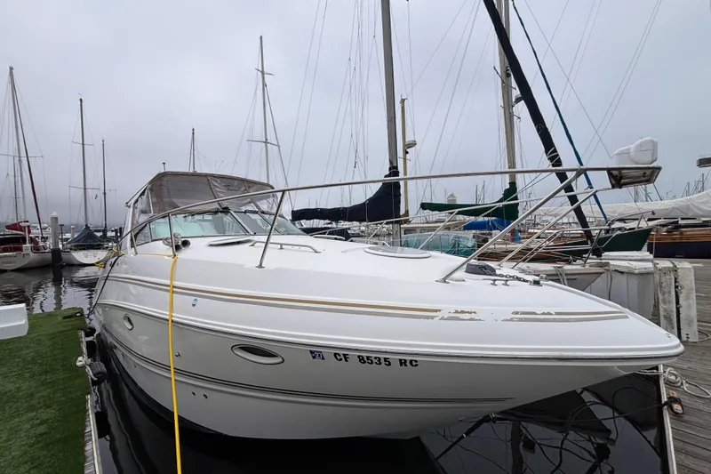 Slide: The Image of 2004 Larson 310 boat docked at marina, surrounded by sailboats on a cloudy day. - 7