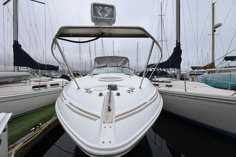 Slide: The Image of 2004 Larson 310 boat docked at marina, surrounded by sailboats on a cloudy day. - 9