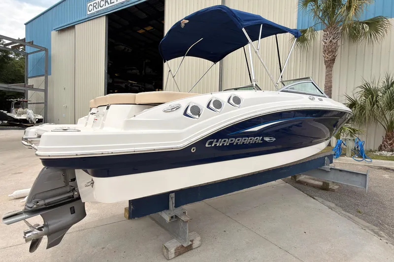 Slide: The Image of 2012 Chaparral 216 SSi boat with blue hull and canopy, displayed outside a warehouse. - 5