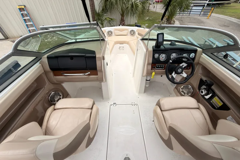 Slide: The Image of Interior view of a 2012 Chaparral 216 SSi boat, featuring beige seating and a modern dashboard. - 13
