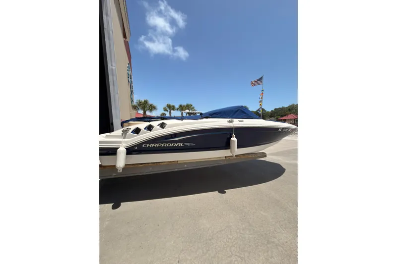 Slide: The Image of 2012 Chaparral 216 SSi boat with cover, parked outdoors under clear sky. - 6