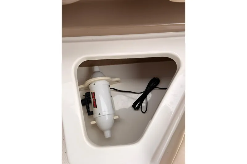 Slide: The Image of 2012 Chaparral 216 SSi boat compartment with installed pump and coiled cable. - 31