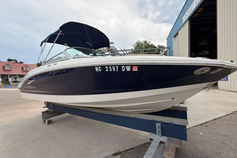 Slide: The Image of 2012 Chaparral 216 SSi boat with blue hull on a trailer, parked outside a building. - 4