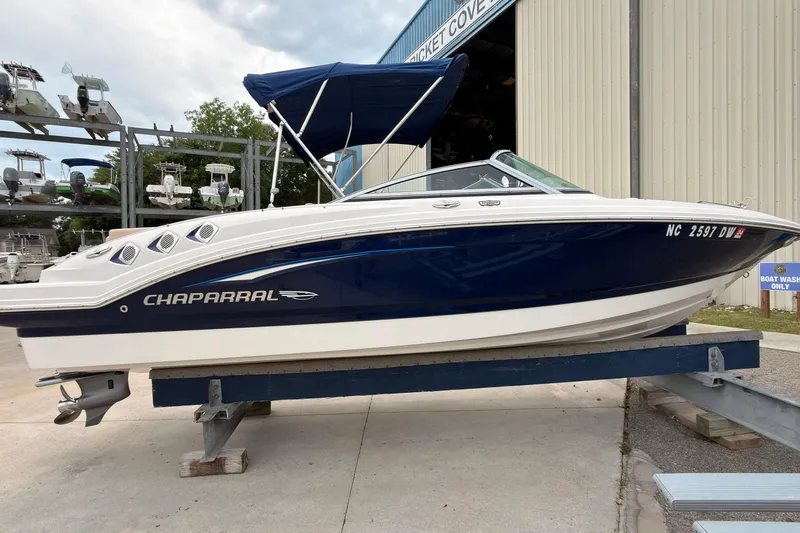 Slide: The Image of 2012 Chaparral 216 SSi boat on display at a marina with blue and white exterior. - 3