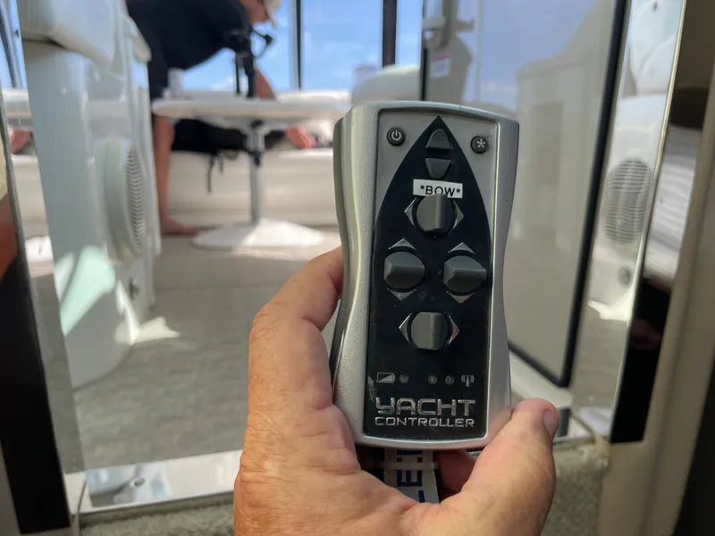 Slide: The Image of A hand holds a yacht controller on a boat. The boat's interior is visible in the background. - 11