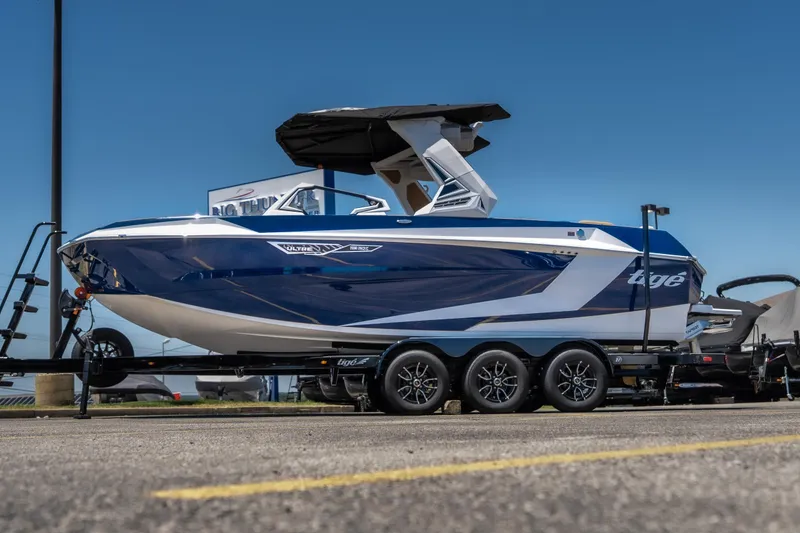 The Image of 2026 Tigé Ultré 23ZX boat on trailer, blue and white design, parked outdoors. - 1