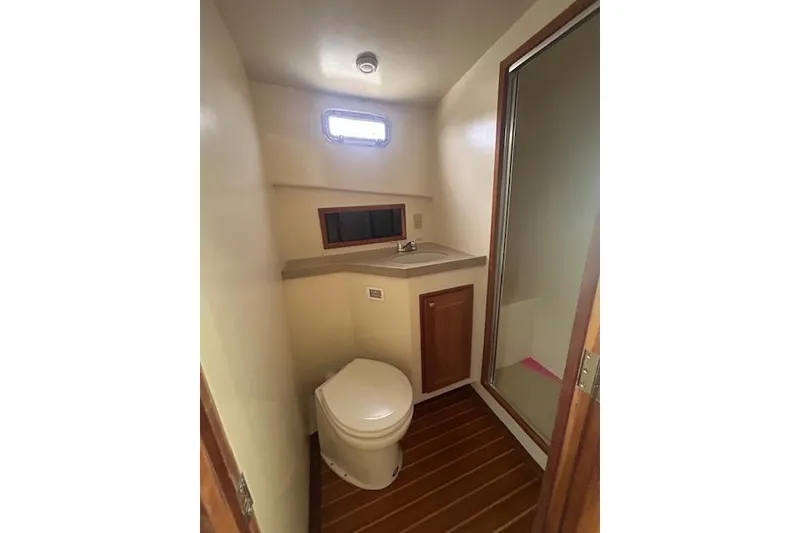 Slide: The Image of Compact boat bathroom with toilet, sink, and shower; wooden flooring and small window. - 23