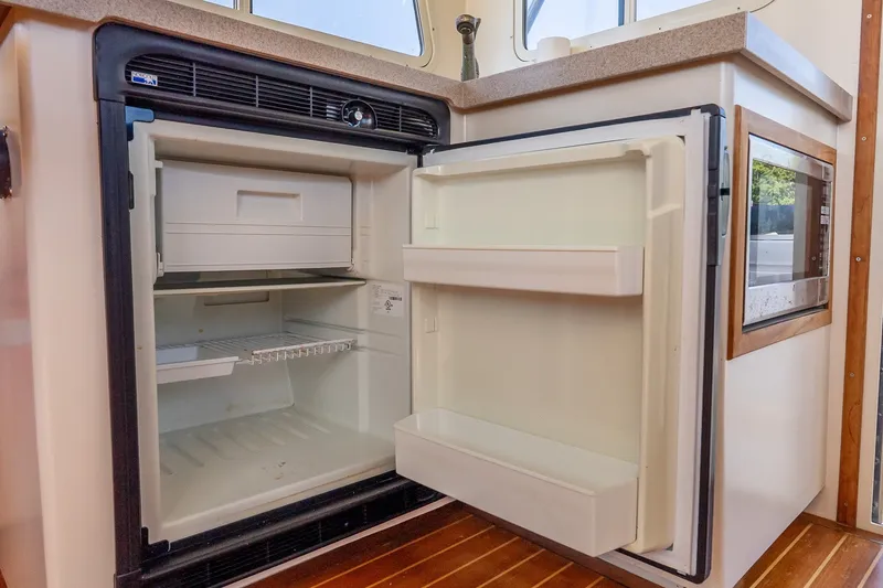 Slide: The Image of Open refrigerator in a kitchen setting, showcasing empty shelves and a freezer compartment. - 32