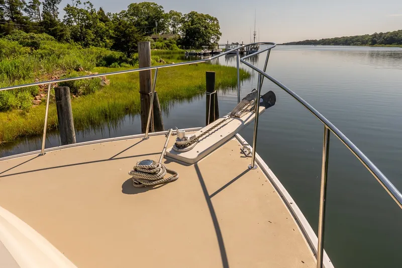 Slide: The Image of Bow of a boat docked by a serene, green shoreline. - 21