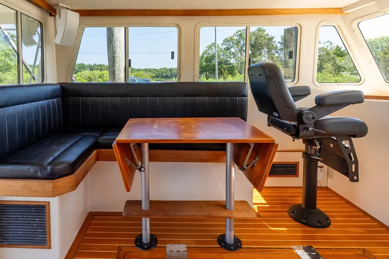 Slide: The Image of Interior of a 2016 Flowers 43 boat with seating and a wooden table. - 26