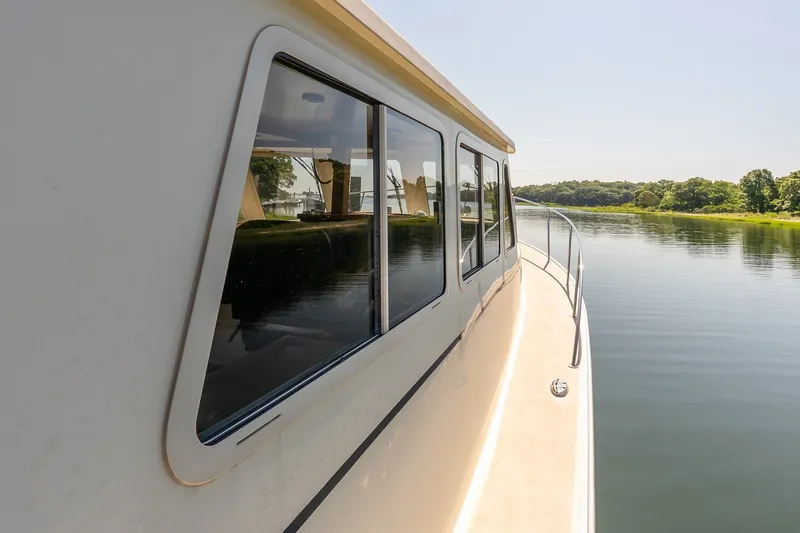 Slide: The Image of Side view of a 2016 Flowers 43 boat cruising on a calm river. - 19