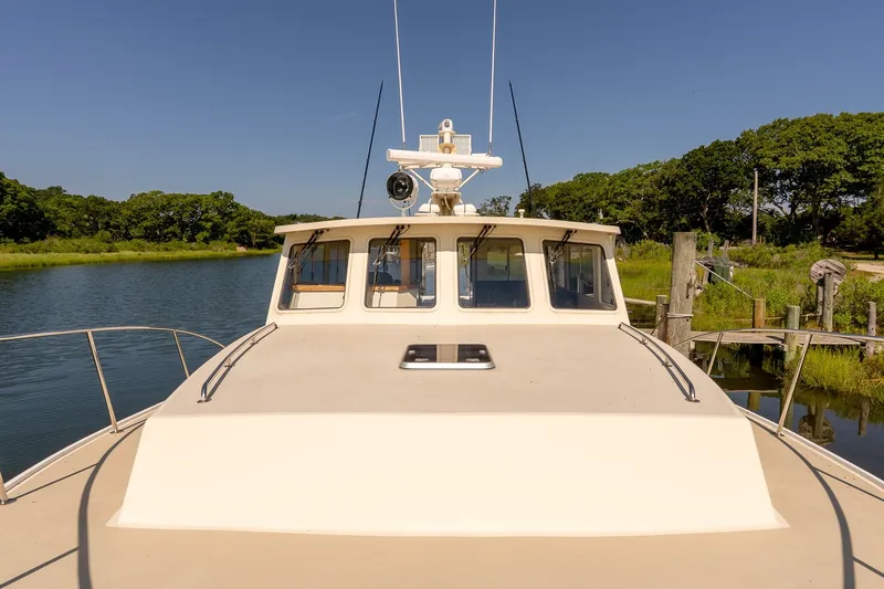 Slide: The Image of Front view of a 2016 Flowers 43 boat docked by a serene riverbank. - 22