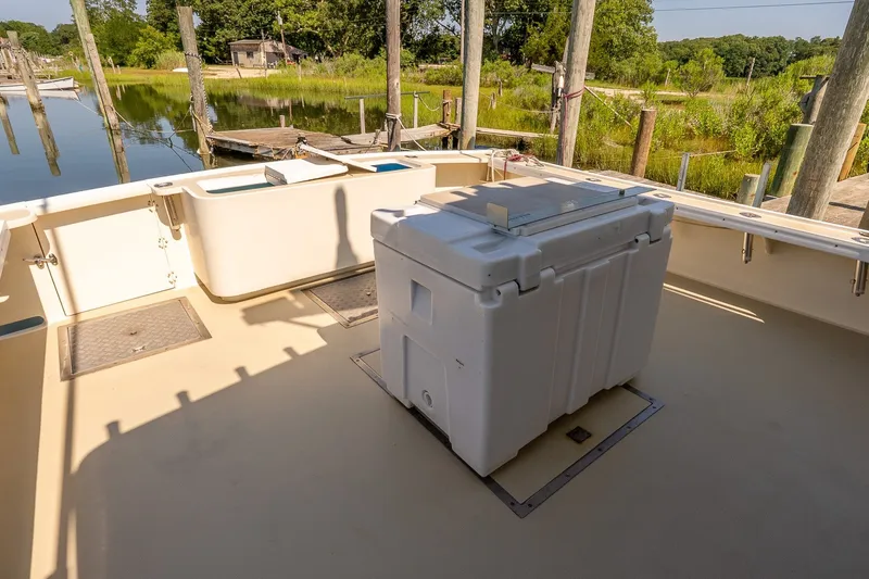 Slide: The Image of Boat deck with storage box, docked near lush greenery and calm water. - 7