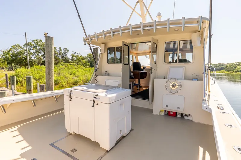 Slide: The Image of Boat deck with seating, cooler, and lush greenery in the background. - 9