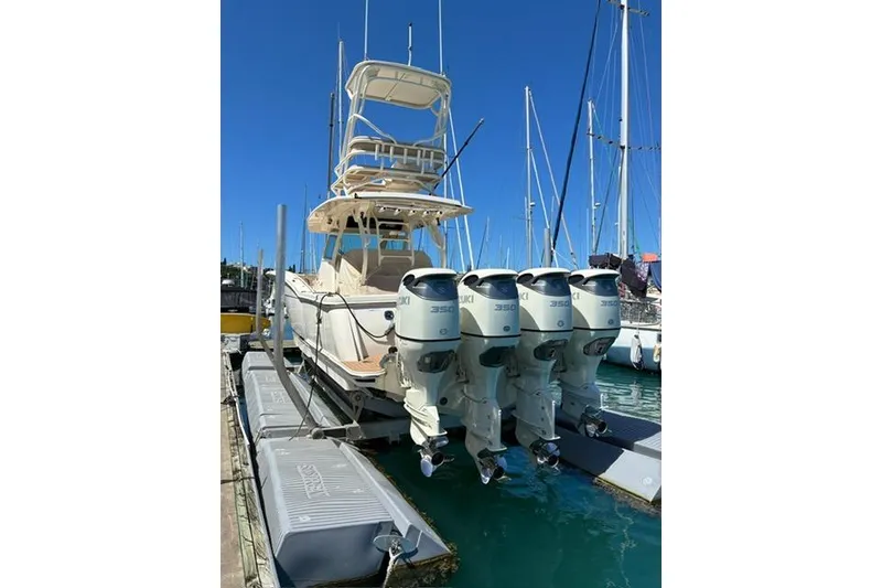 The Image of 2018 Scout 420 LXF boat with four Suzuki outboard engines docked at marina. - 0