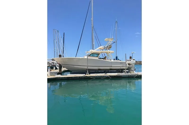 Slide: The Image of 2018 Scout 420 LXF boat docked in a marina under clear blue skies. - 1
