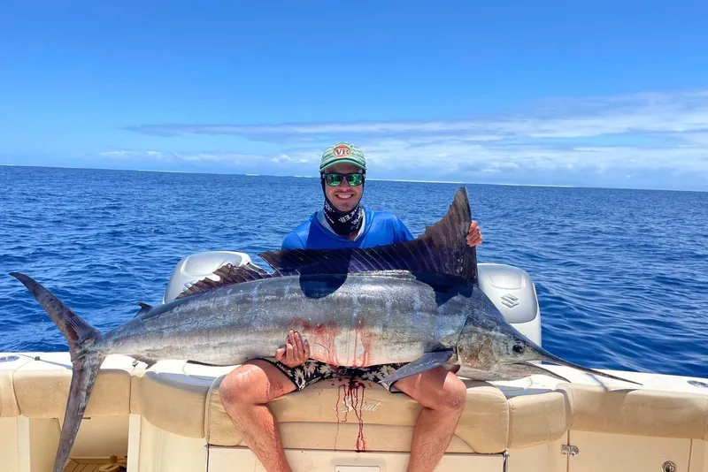 Slide: The Image of Man holding large fish on 2018 Scout 420 LXF boat, ocean backdrop. - 15