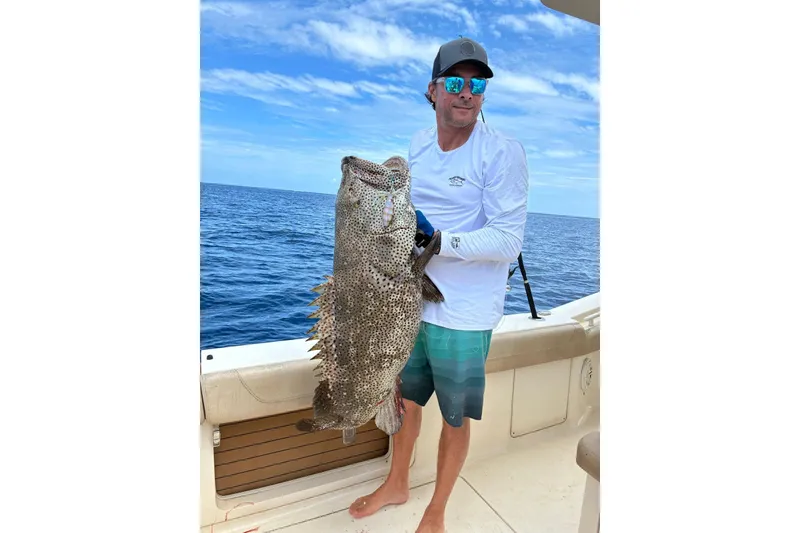 Slide: The Image of Man holding large fish on 2018 Scout 420 LXF boat, ocean backdrop. - 21