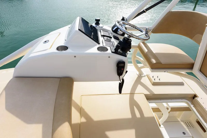 Slide: The Image of Manufacturer Provided Image: 2018 Scout 420 LXF boat helm with beige seating and water backdrop. - 7