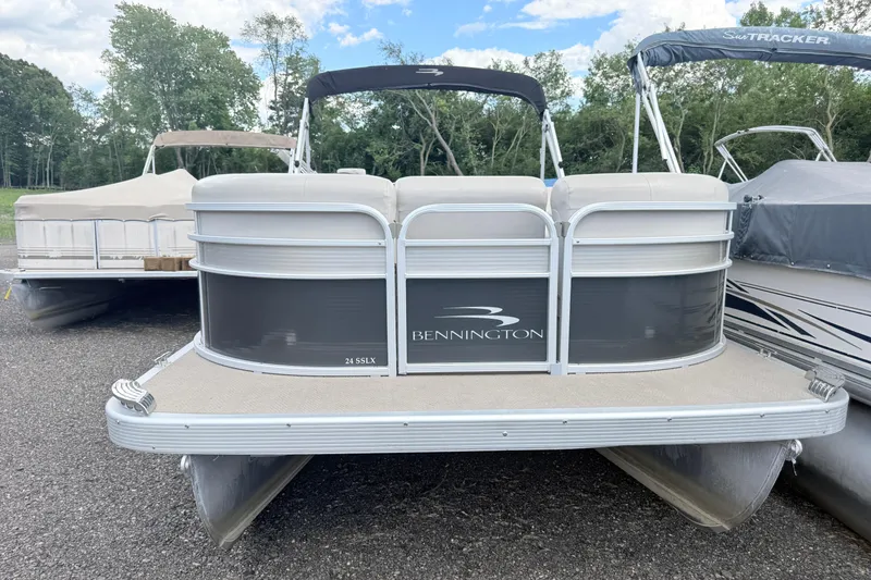 Slide: The Image of 2015 Bennington 24SSLX pontoon boat parked on gravel with trees in background. - 2