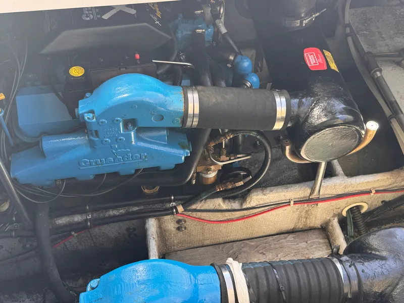 Slide: The Image of An engine compartment with a blue Crusader engine and black hoses. - 24