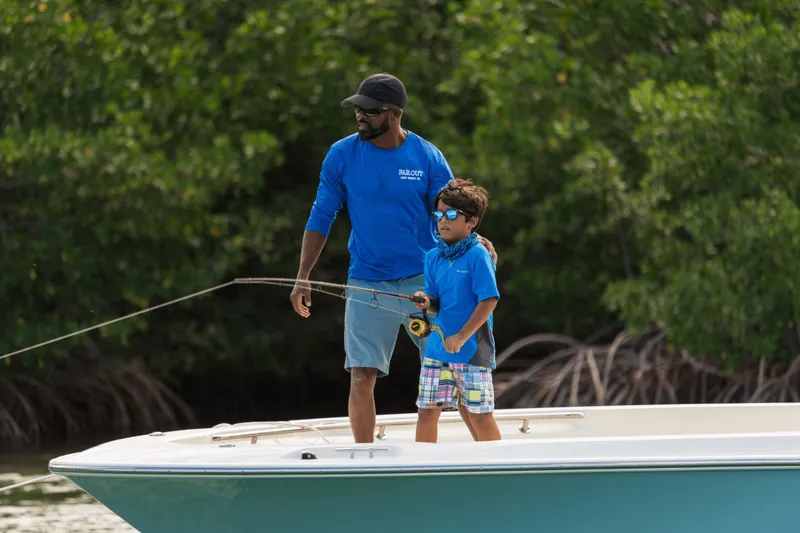 Slide: The Image of A man and child fishing on a boat in a green, wooded area. - 10
