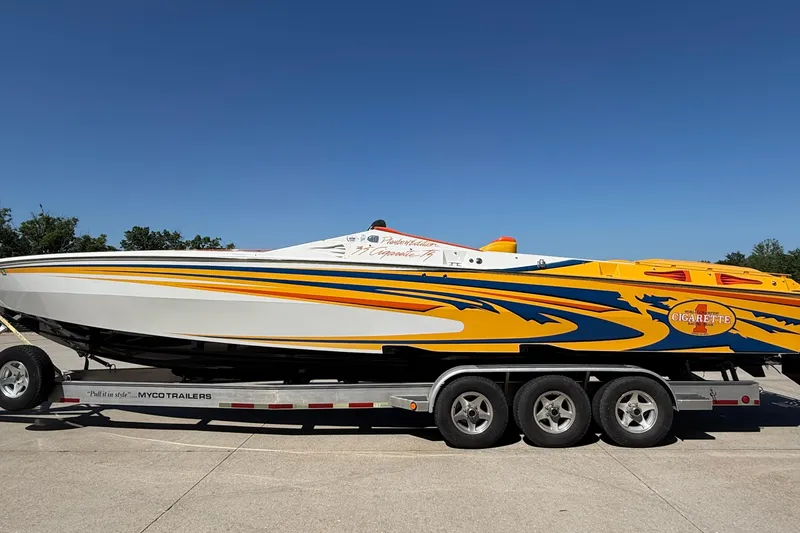 Slide: The Image of 2002 Cigarette 35' Cafe Racer boat on trailer, vibrant yellow and blue design. - 5